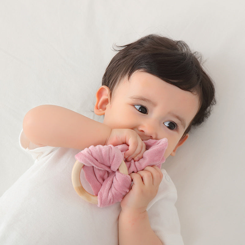 Bunny Ear Baby Comforter with Wooden Ring, shown on a bed