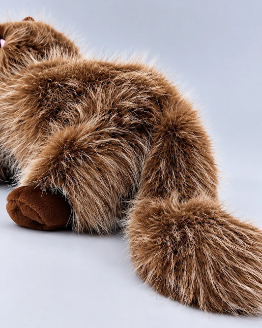 Realistic brown and white Ragdoll-style cat plush toy, lying down, close-up of the tail