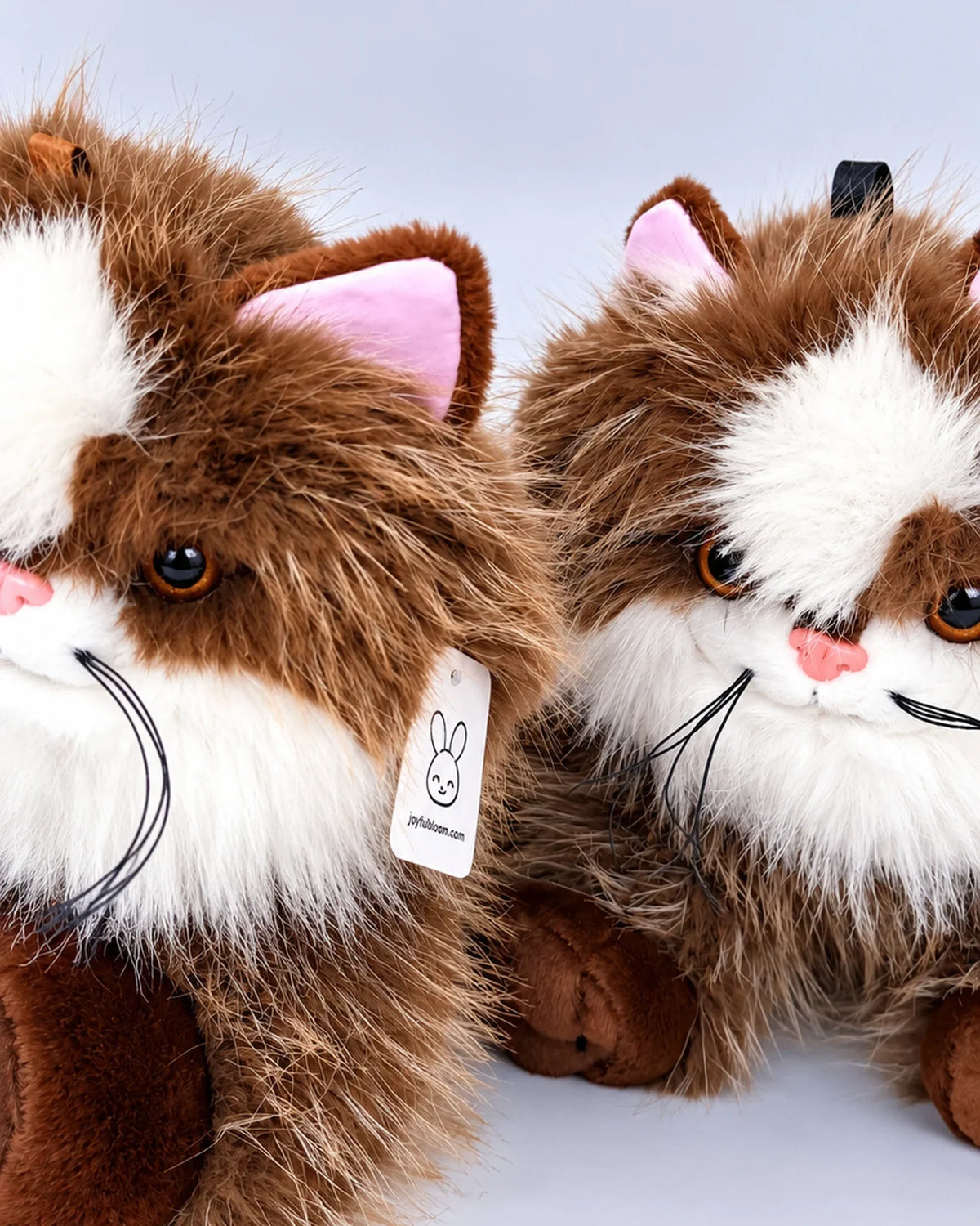 Realistic brown and white Ragdoll-style cat plush toy, lying down, close-up